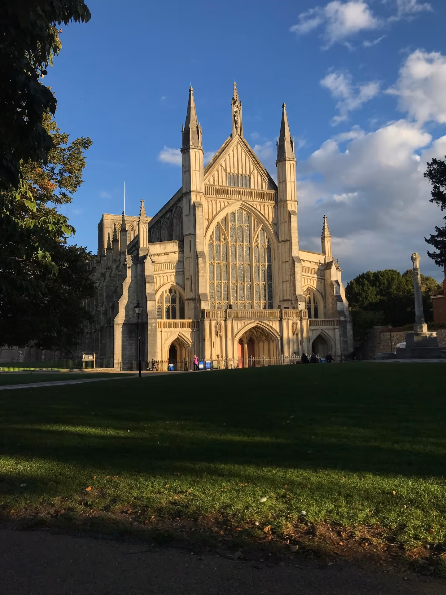 Gothic cathedral with large stained glass windows and spires under a partly cloudy blue sky.